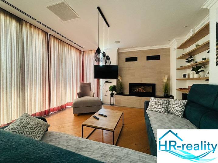 Living room in a villa with a fireplace, TV, wooden decor flooring, and comfortable seating.