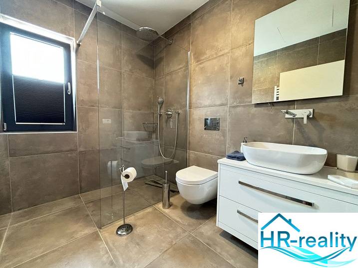 A bathroom in a villa with a large shower and a wall-mounted toilet.
