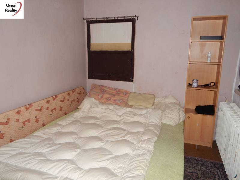 A room with a bed, a shelf, and a radiator, suitable for renovation of catering spaces.