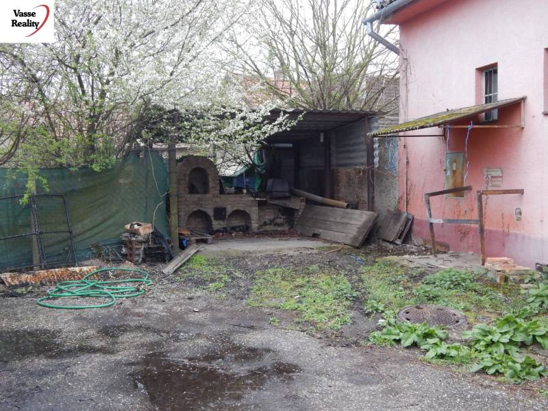 Exterior in dining spaces in Búč with an old oven and spring vegetation.