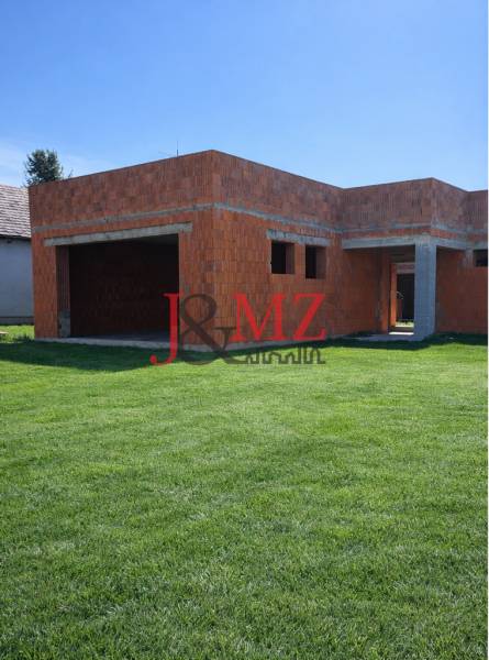 An unfinished family house in Dolná Seč with a grassy plot and brick foundations.