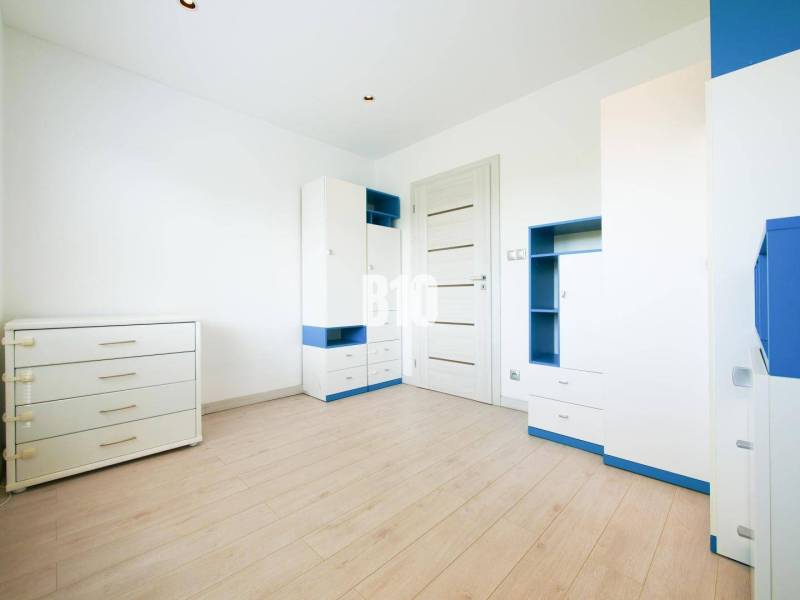 Children's room in a three-room apartment with white and blue furniture, wooden decor flooring.