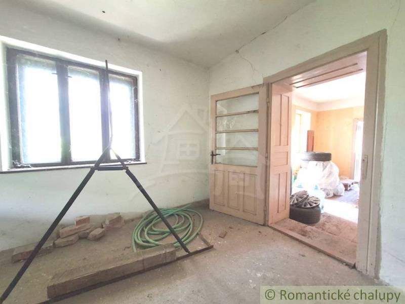 A room in a cottage with light from the window, open doors, and construction mess.