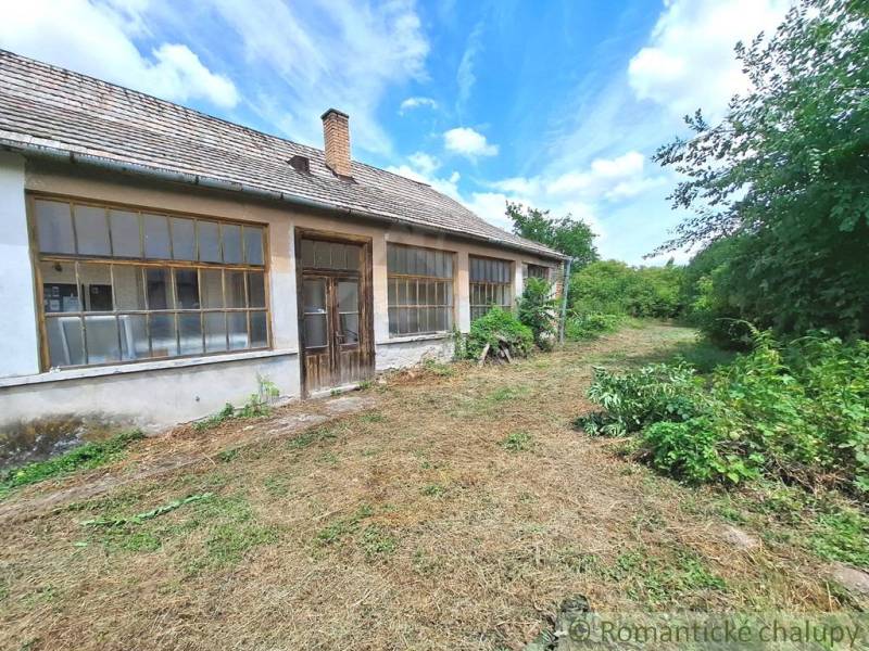 An old house in the gardens of Kamenný Most surrounded by lush greenery and trees.