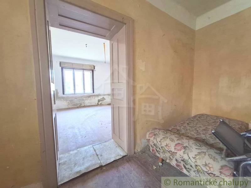 A room in a cottage with old furniture and a window, waiting for renovation.