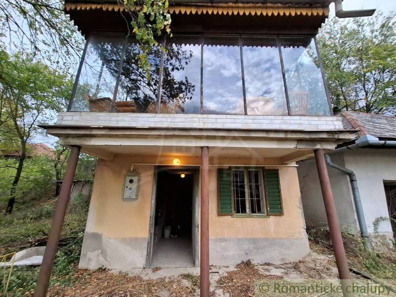 A cottage in Kamenín with a glass terrace, surrounded by nature and trees.