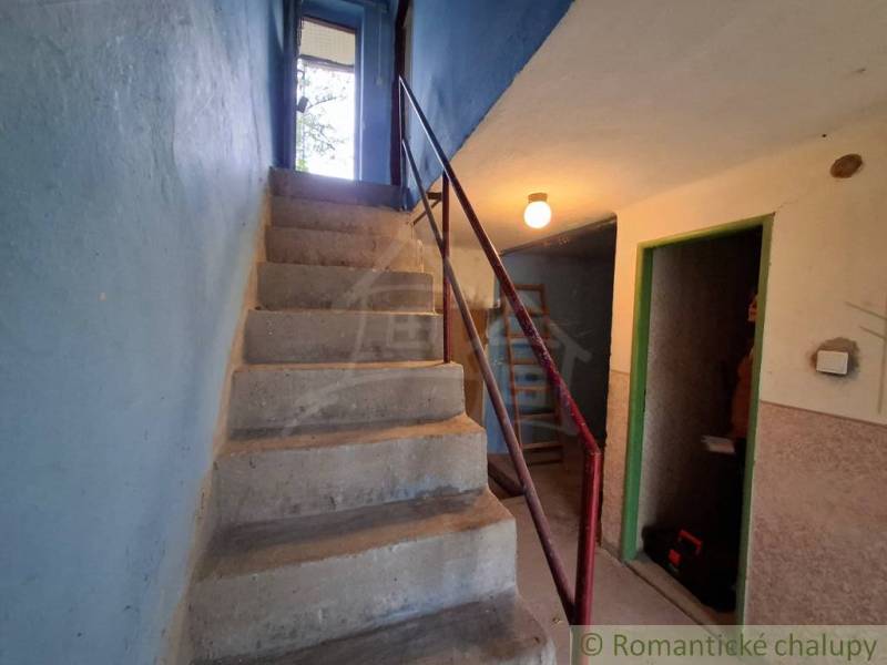 Concrete stairs in the interior of a cottage with blue walls and metal railing.