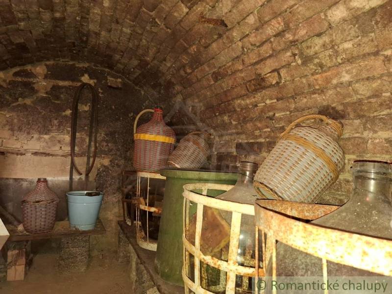 A wine cellar at the cottage with stones and demijohns in Kamenín.
