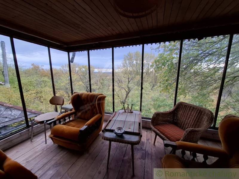 A cottage with a view of nature, comfortable armchairs, and a floor with a wooden decor.