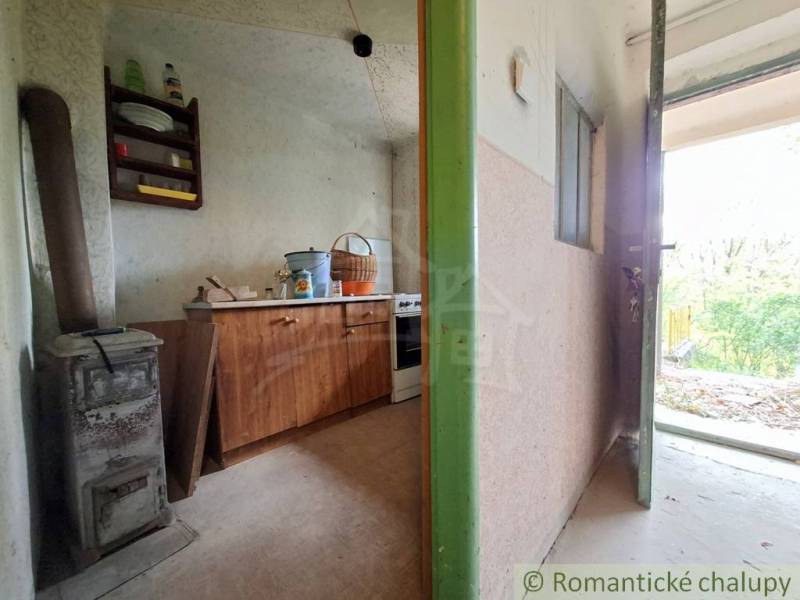 Interior of a cottage with an old stove and furniture on the floor with wooden decor.