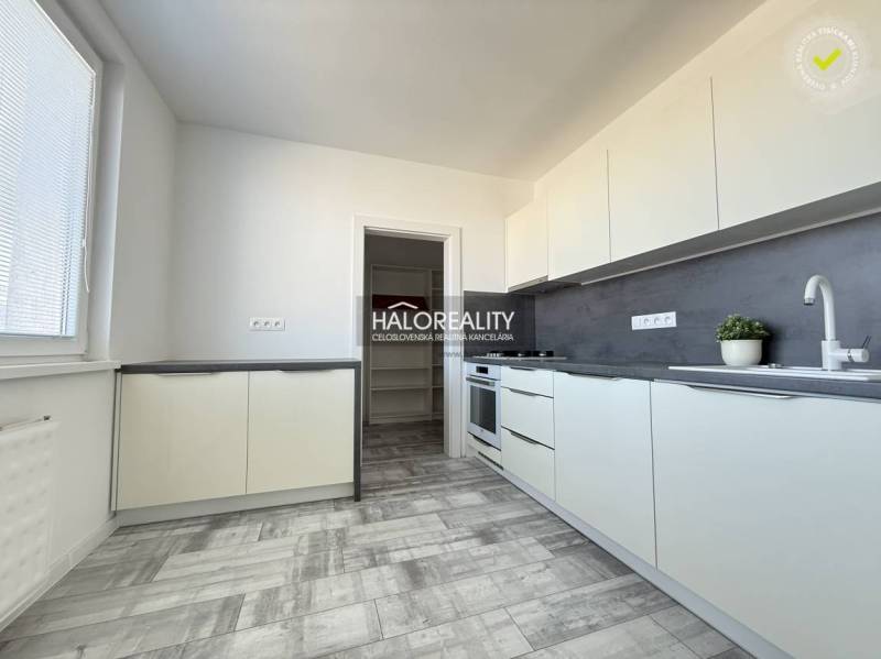 A kitchen in a 2-room apartment with a wooden decor floor and light furniture.