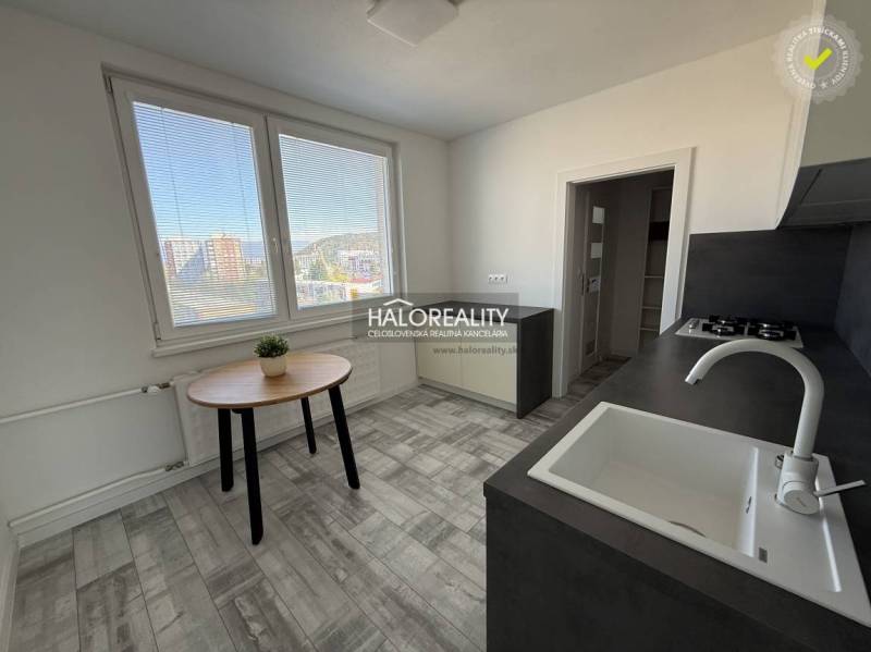 A kitchen in a 2-room apartment with a view, wooden decor flooring, simple furniture.