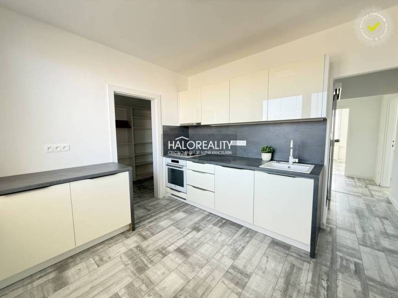 A kitchen in a 2-room apartment with white cabinets and a wood-patterned floor.