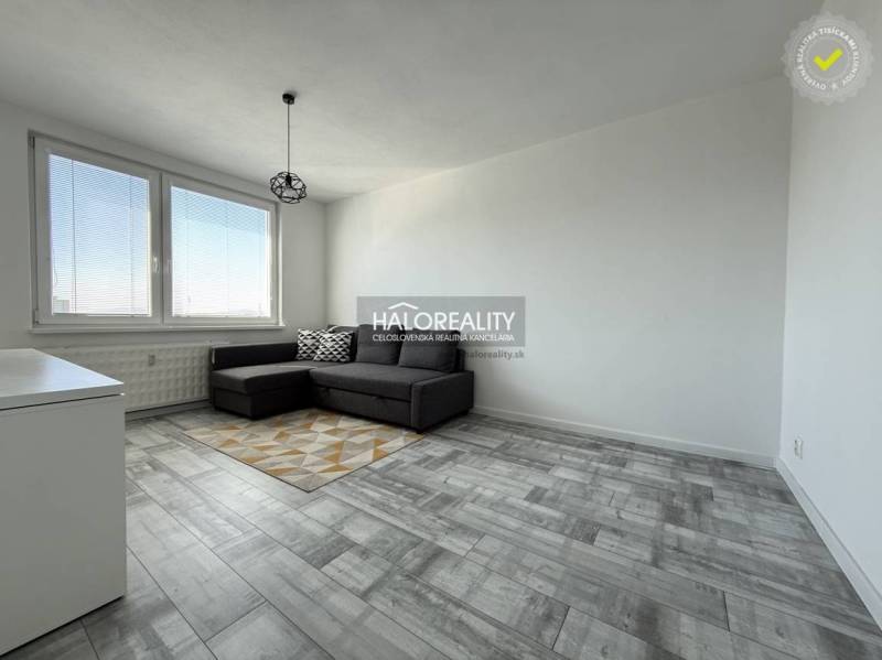 Living room in a two-room apartment with a wooden decor floor and a gray sofa.
