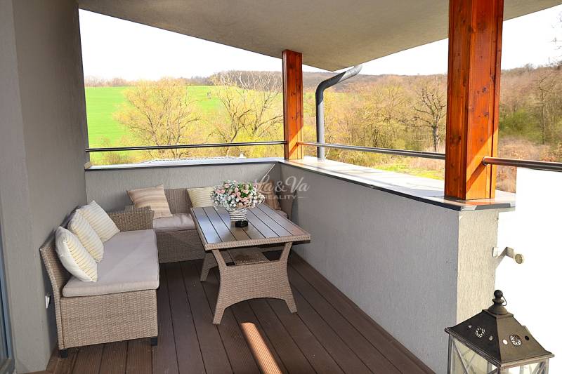 A spacious balcony with rattan furniture and a wooden decor floor in a studio apartment.