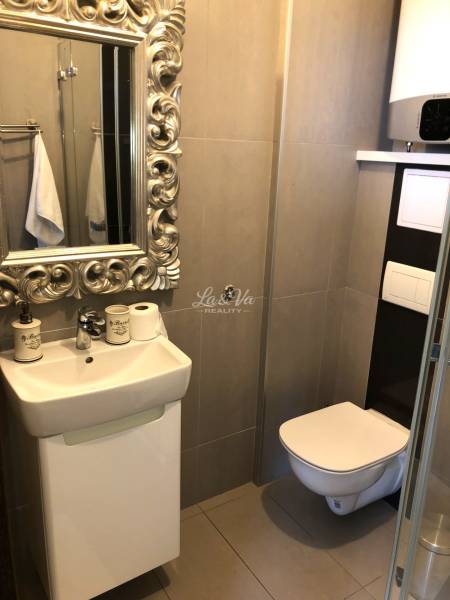 A bathroom in a 2-room apartment with a timeless mirror, sink, and wall-mounted toilet.