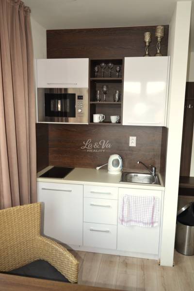 A compact kitchenette in a 2-room apartment with white cabinets and appliances.