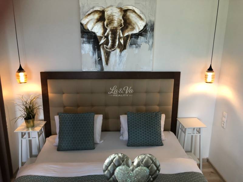 A bedroom with stylish lighting and a picture of an elephant in a 2-room apartment.