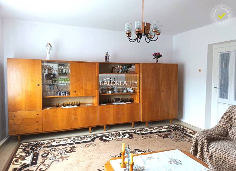 Living room in a family house with a wooden wall unit and a chandelier.