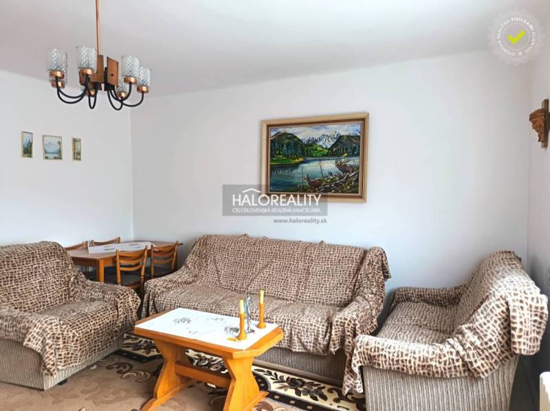 Living room of a family house with a sofa, painting, and dining table.