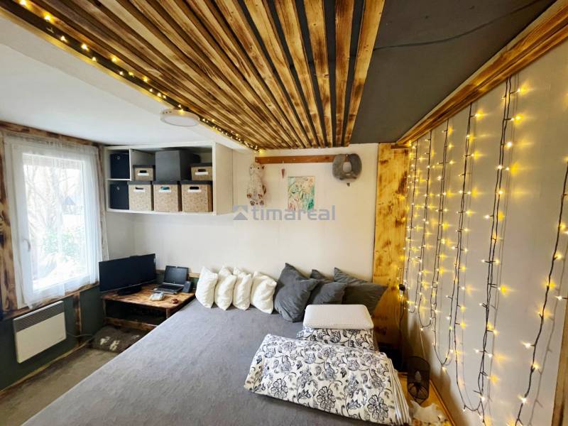 Interior of a family house with string lights, wood-patterned flooring, and a comfortable bed.