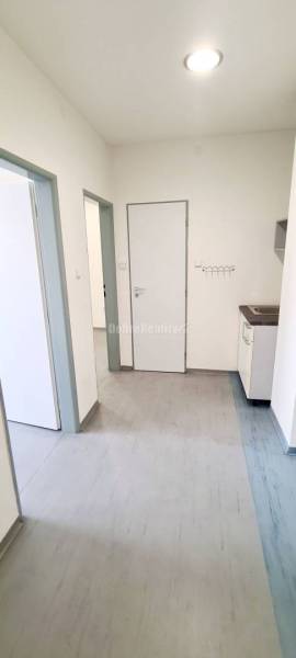 The interior of offices with laminate flooring and white walls, a kitchen unit in the corner.