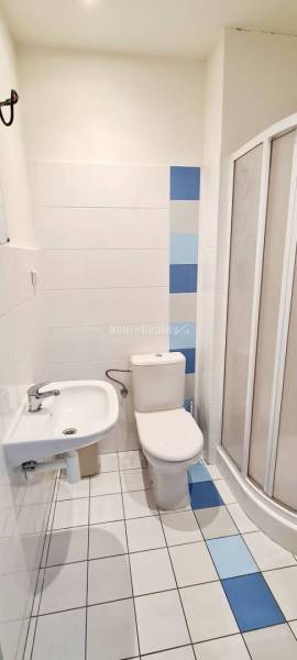 Office bathroom with ceramic tiles, a shower corner, and white tiles.