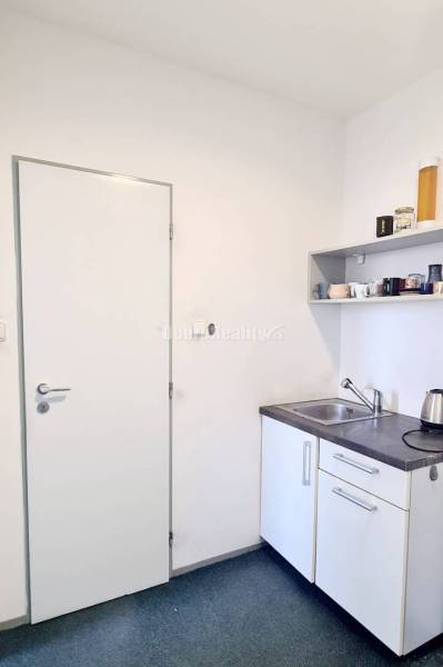 A small office kitchenette with a sink, a shelf, and a kettle.