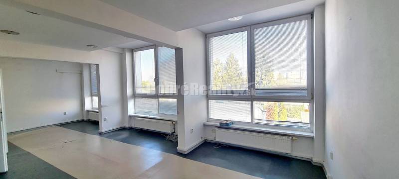 A spacious office with large windows and a wooden decor floor.