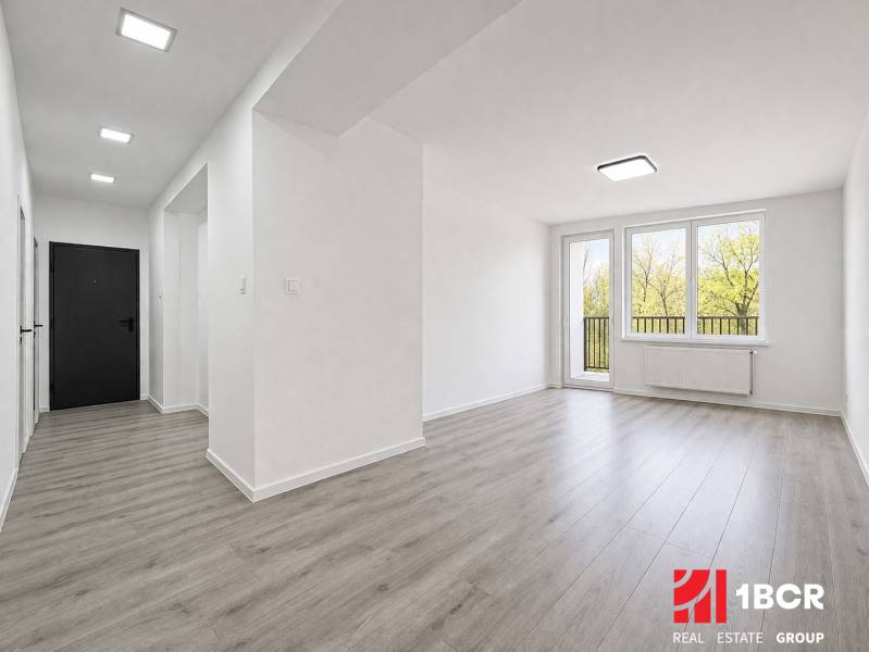 A bright interior of a 3-room apartment with a wooden decor floor and large windows.