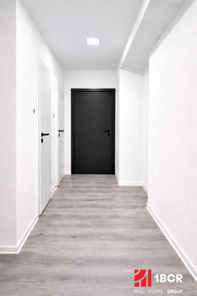 A corridor with light walls and a wooden decor floor in a 3-room apartment.