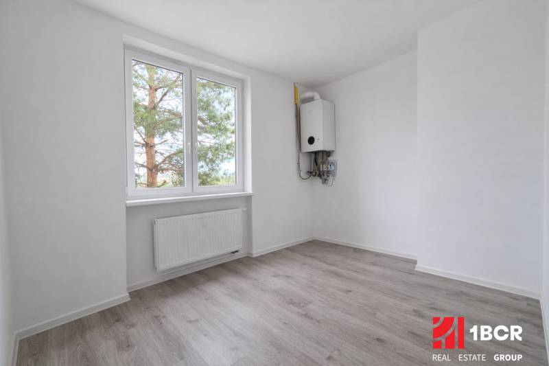 A room in a 3-room apartment with a wood-patterned floor and a radiator.