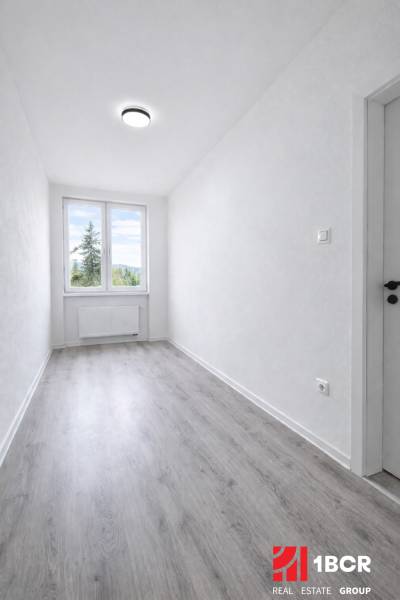 A narrow room with a large window and a floor with wood decor in a 3-room apartment.