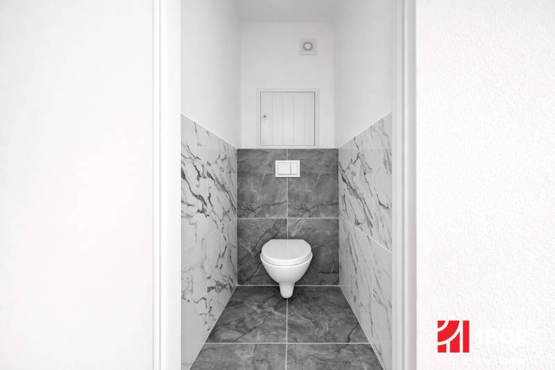 A toilet with marble tiles in a 3-room apartment.
