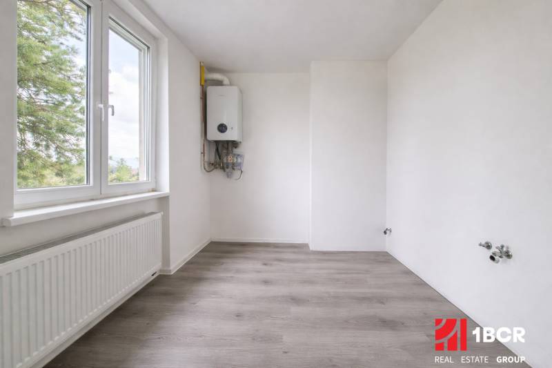 A room with white walls and a wooden decor floor in a 3-room apartment.