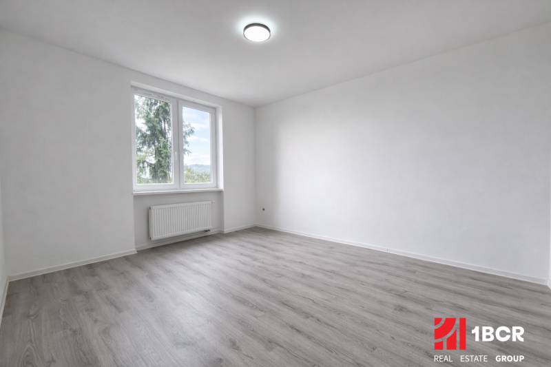 A spacious room with a window and a wooden decor floor in a 3-room apartment.
