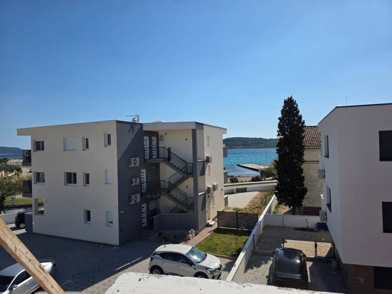 Buildings near the sea in the town of Srima, with a view of the coast and cars in the parking lot.