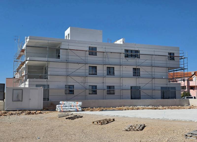 A building in the city of SRIMA with scaffolding and mess on the ground.