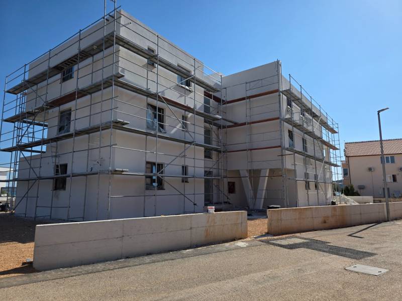 A construction project of a 3-room apartment in SRIMA, surrounded by scaffolding in sunny weather.