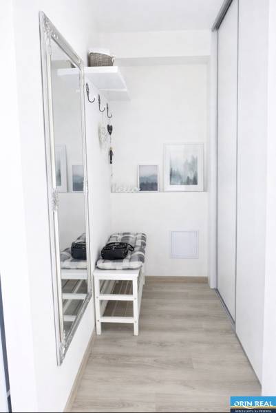 Entrance hall in a 2-room apartment with a mirror, bench, and wooden decor flooring.