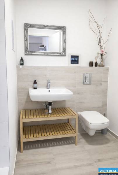 Bathroom with a sink and mirror, simple decoration and light wall tiles in a 2-room apartment.
