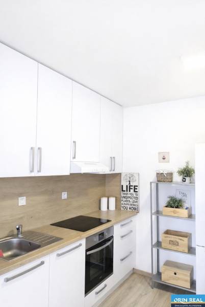 A bright kitchen in a 2-room apartment with white cabinets and decorative accessories.