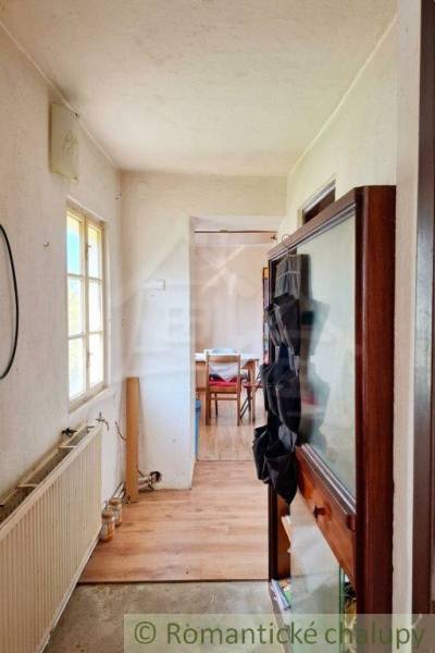 The interior of a family house with a narrow hallway and a room at the end.