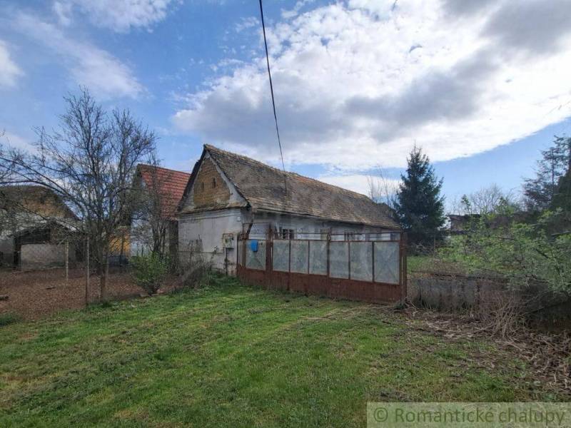 A family house in Ozdín, surrounded by a garden and trees, under a blue sky.