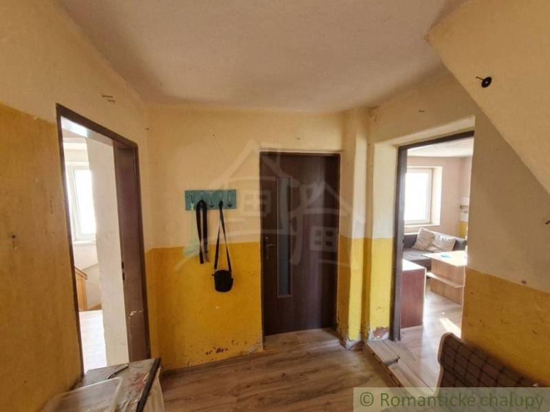 Interior of a family house with a wooden decor floor, yellow walls, coat rack, sofa.
