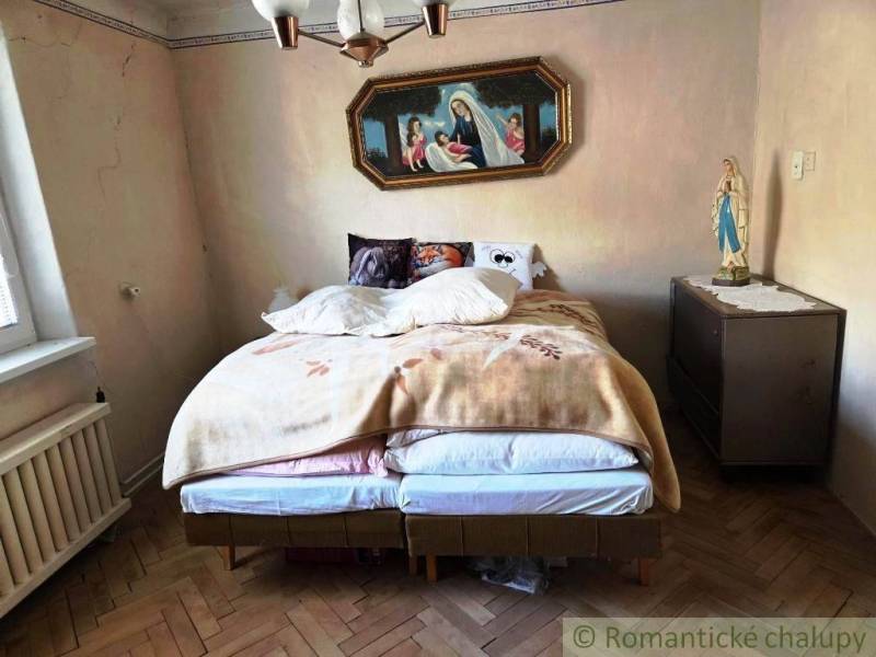 A bedroom in a family house with a bed and religious decoration on the wall.
