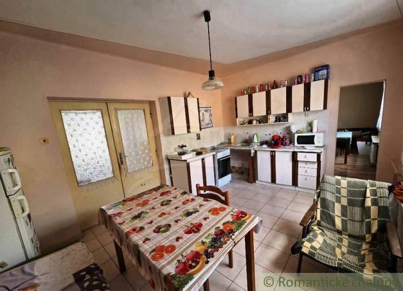 A kitchen in a family house with a dining table, kitchen unit, and appliances.