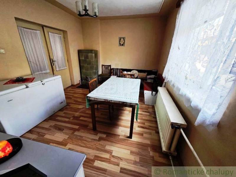 Dining room in a family house with a wooden decor floor and a tiled stove.