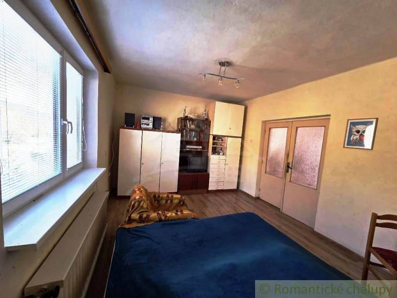 A room with a wooden floor design, a bed, a wardrobe, and a decorative painting in a family house.