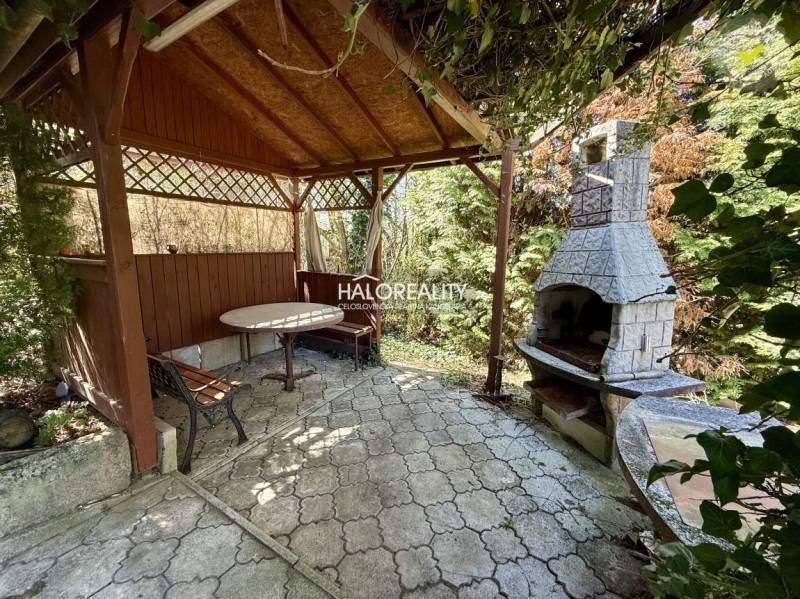 Pergola with a table and a fireplace in the gardens of Rimavská Sobota.